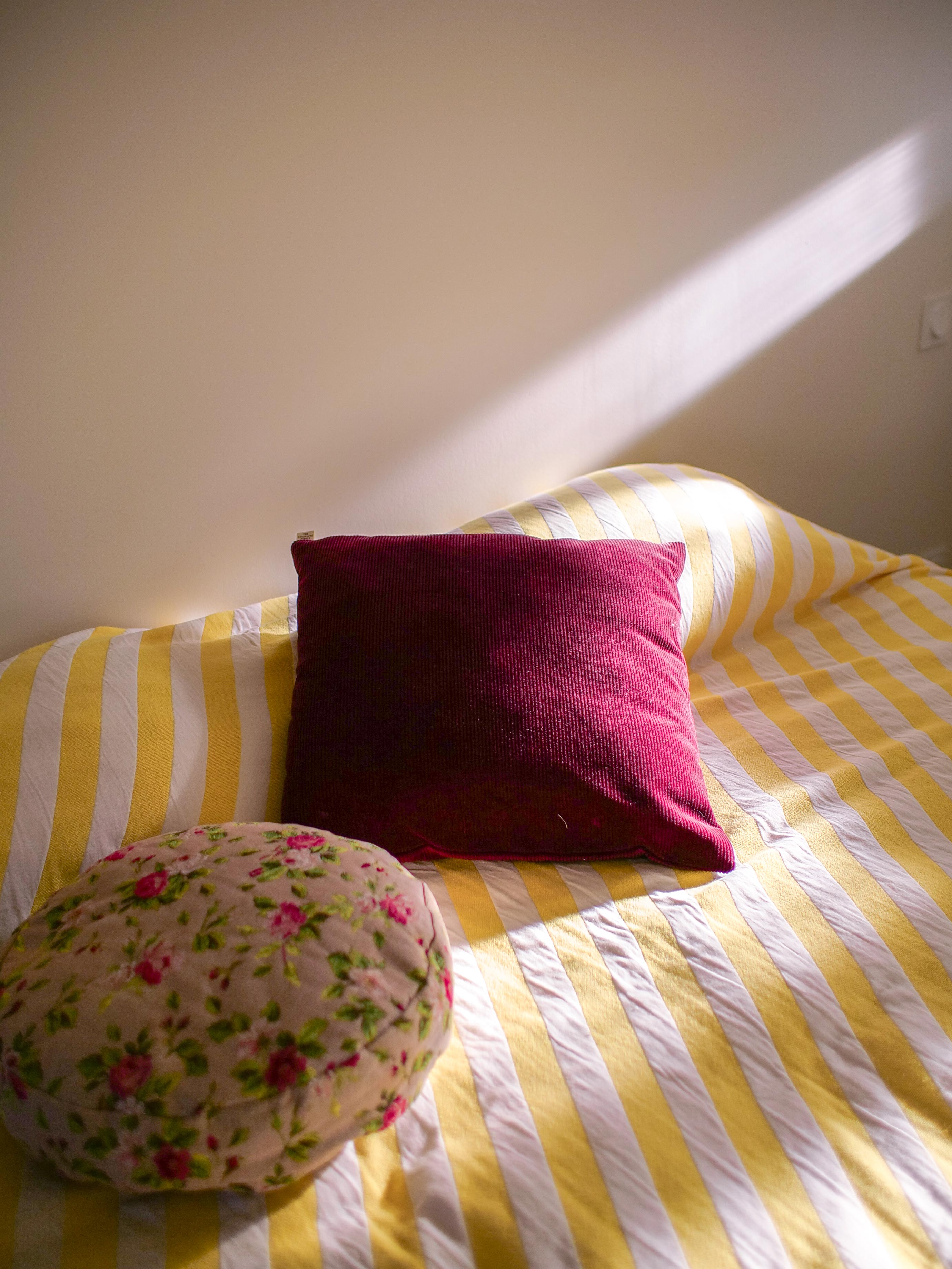 Lit avec linge rayé jaune et blanc et coussins dans la suite de l'Atelier Latresne