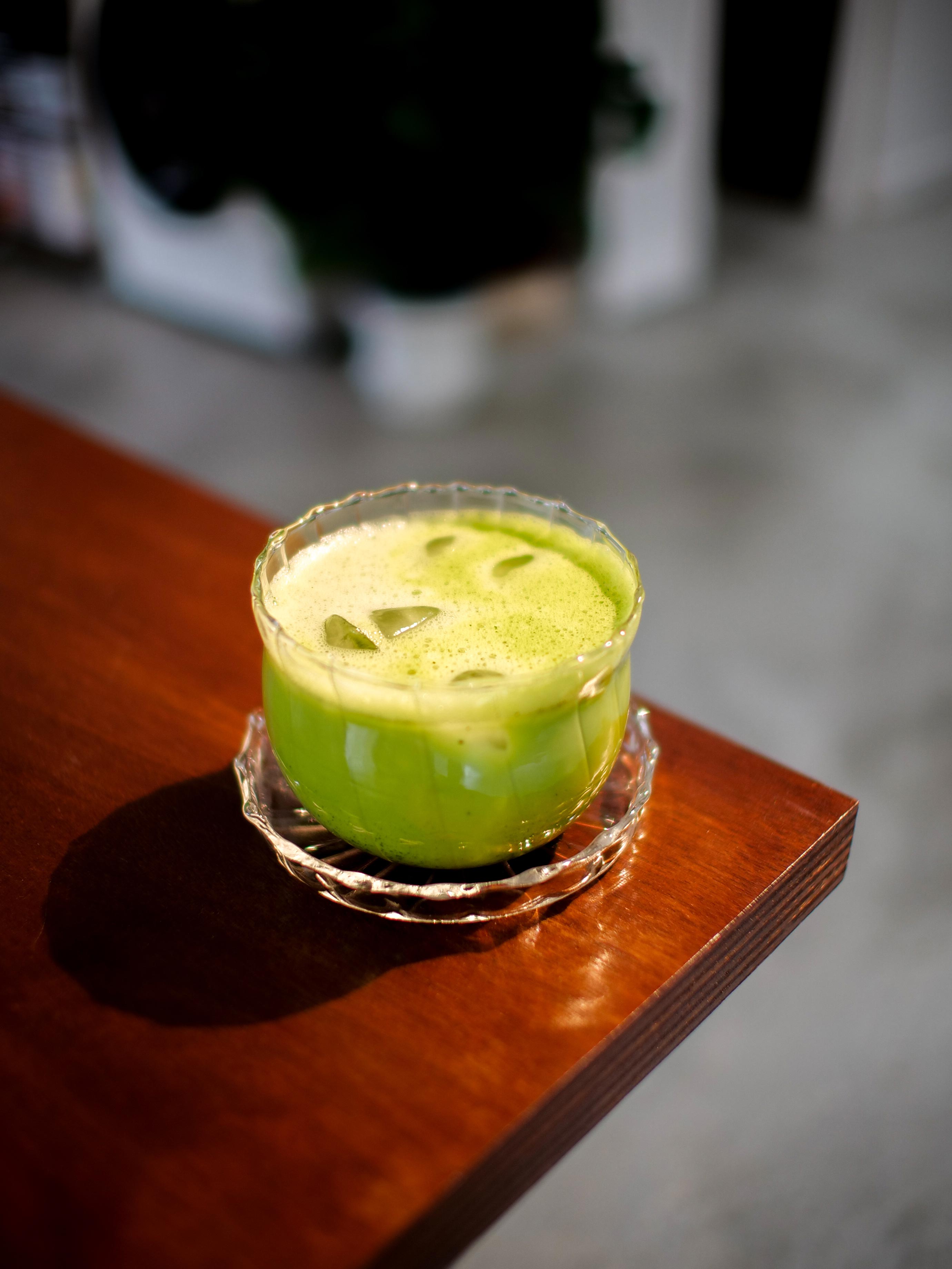 Verre de matcha latte glacé posé sur une table en bois à l'Atelier Latresne