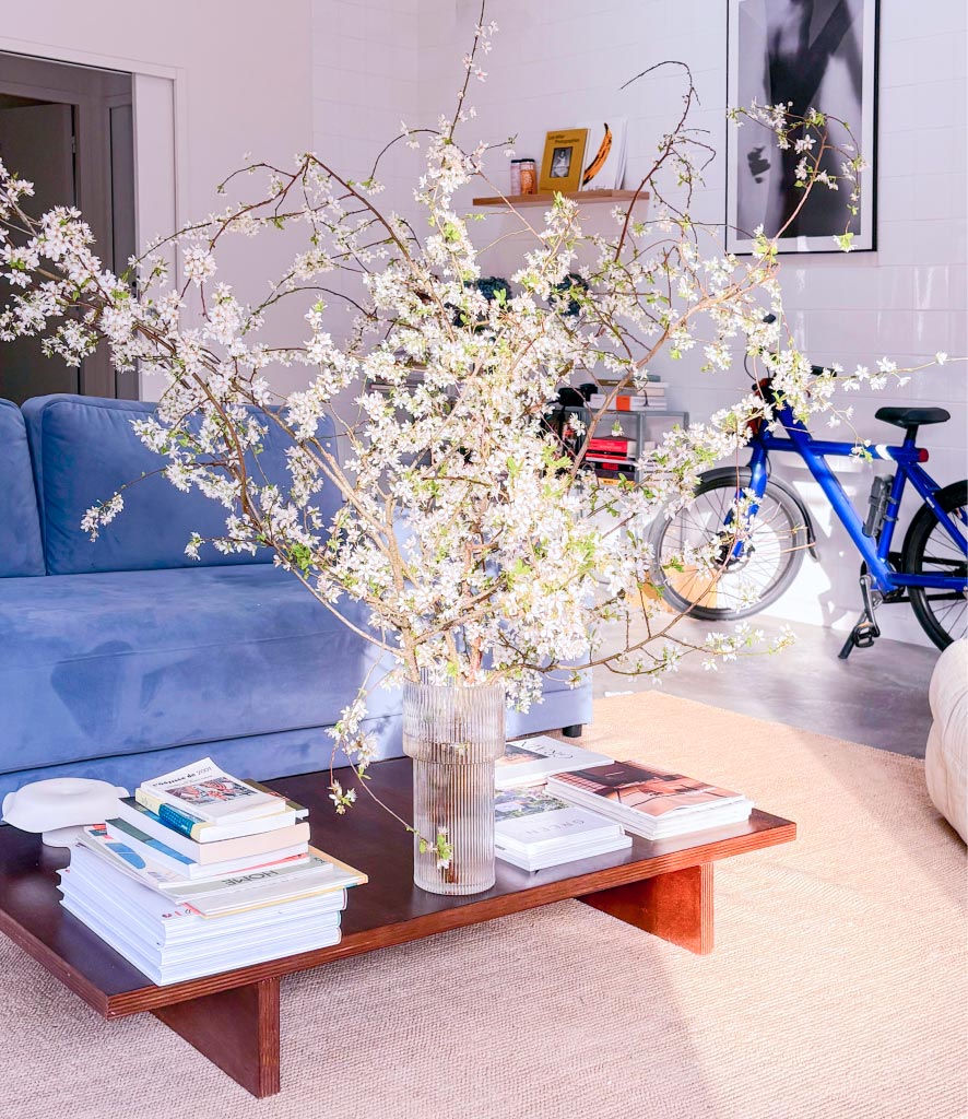 Salon avec canapé bleu et bouquet de fleurs de cerisier sur la table basse, à l'Atelier Latresne