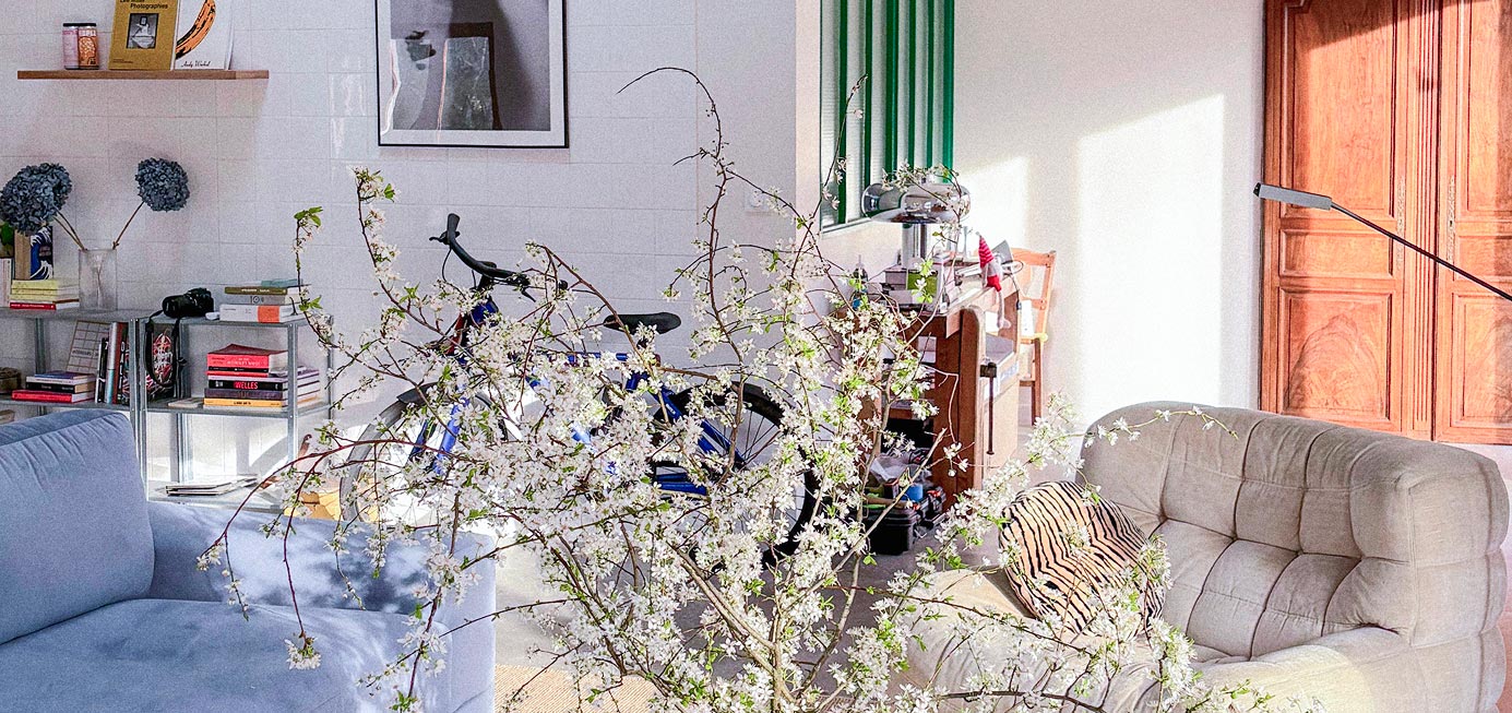 Salon de l'Atelier Latresne avec canapé bleu, vélo et bouquet de fleurs de cerisier