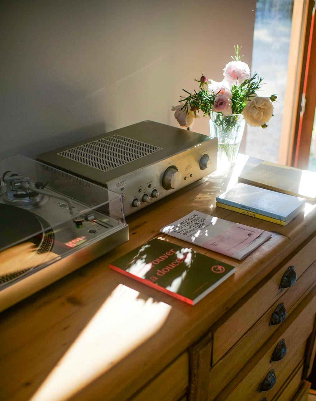 Commode en bois avec platine vinyle et bouquet de roses dans le séjour