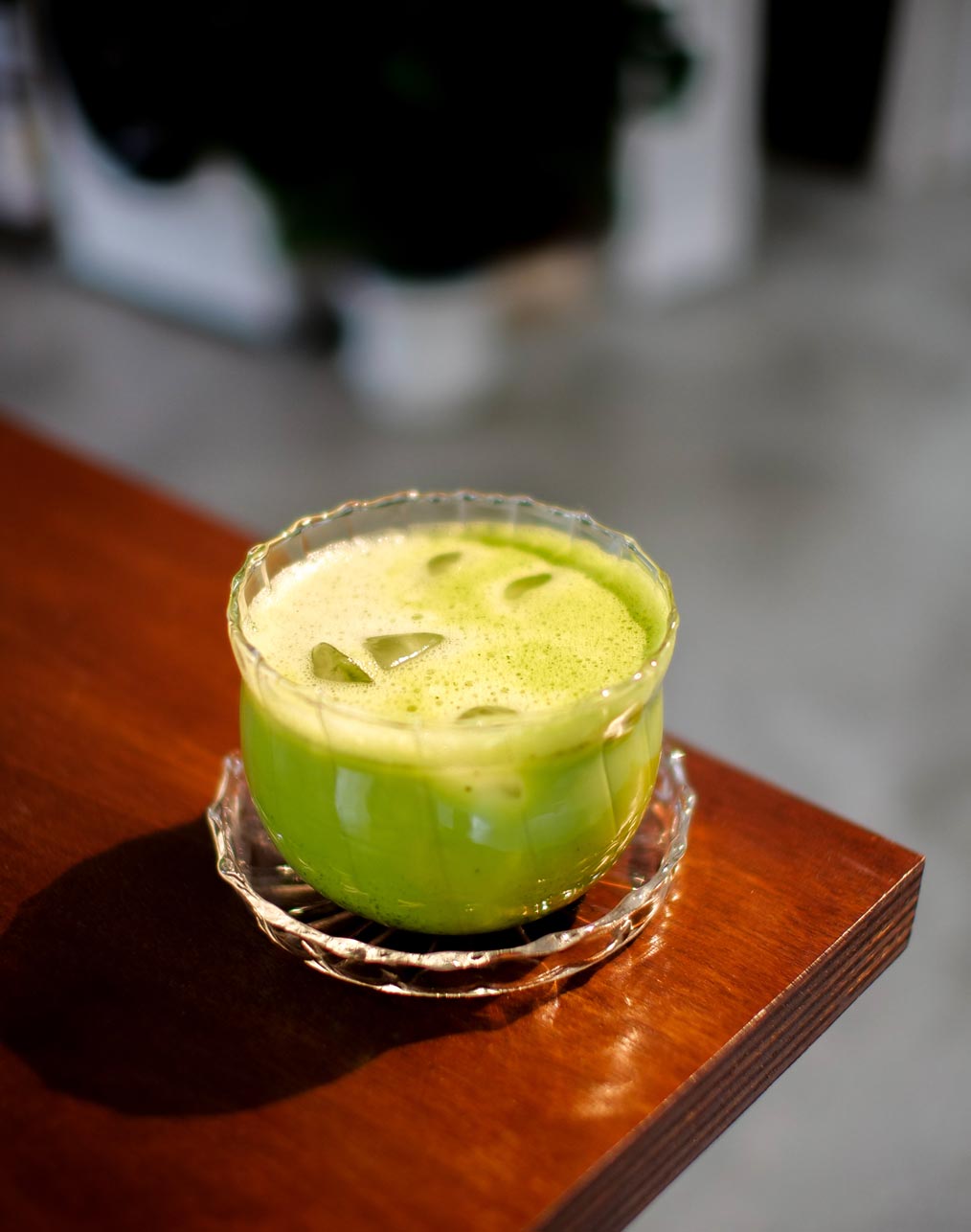 Verre de matcha latte glacé posé sur une table en bois à l'Atelier Latresne