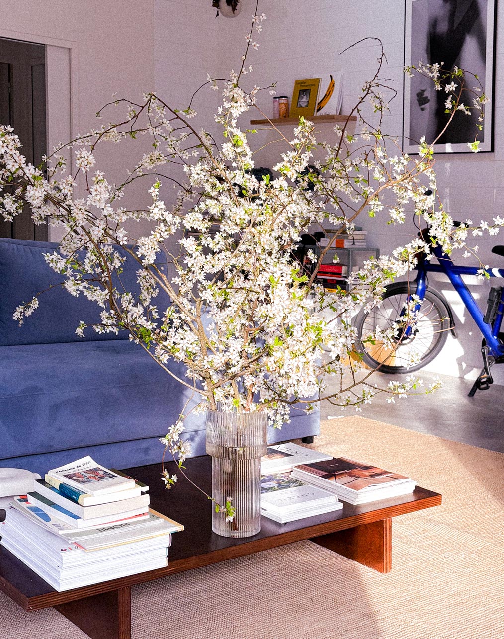 Salon avec canapé bleu et bouquet de fleurs de cerisier sur la table basse, à l'Atelier Latresne